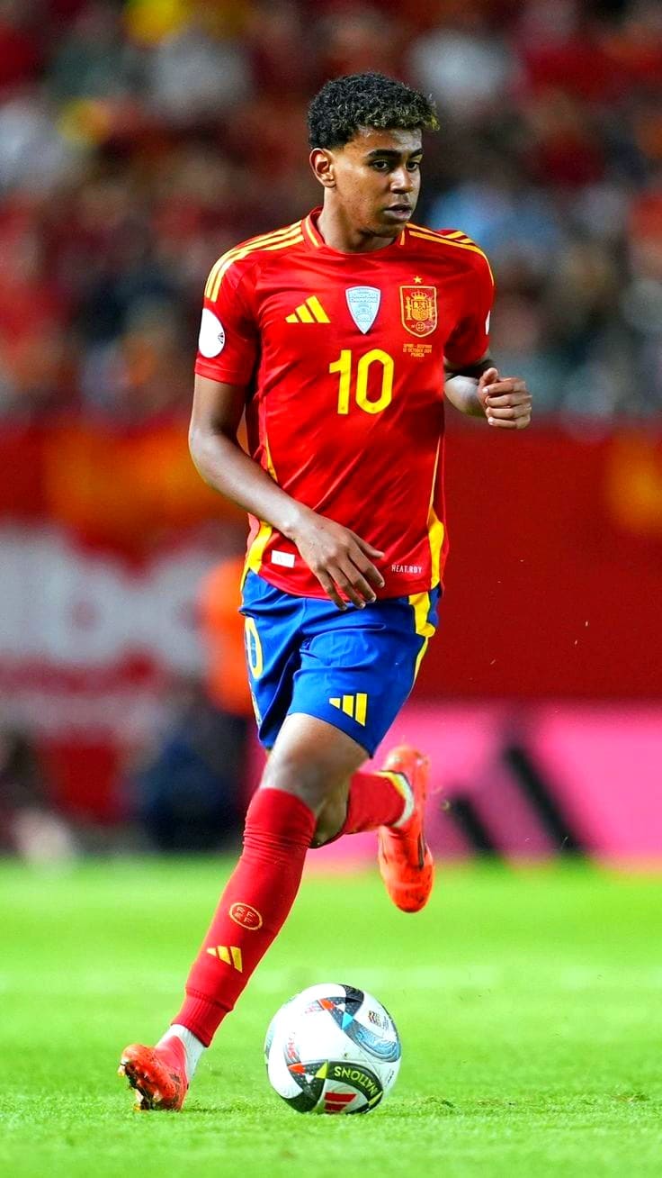 Viking IPTV A male soccer player in a red and yellow Spain jersey with the number 10 dribbles a ball on the field during a match, broadcast live on IPTV Latino. The background shows a blurred crowd.